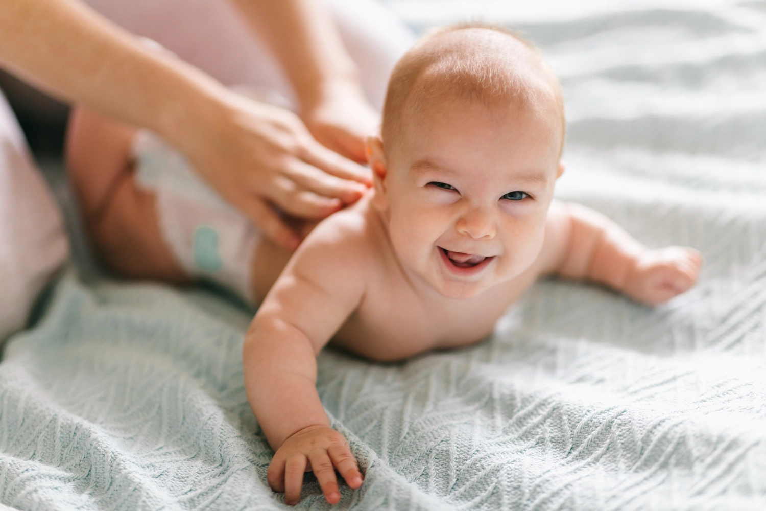 Antonia Schäffler – Hebammenpraxis Eggenfelden – Dieses Bild zeigt eine Person, die ein glückliches Baby massiert, eine Praxis, die sowohl dem Kind als auch der Pflegekraft viele körperliche und emotionale Vorteile bringt.
