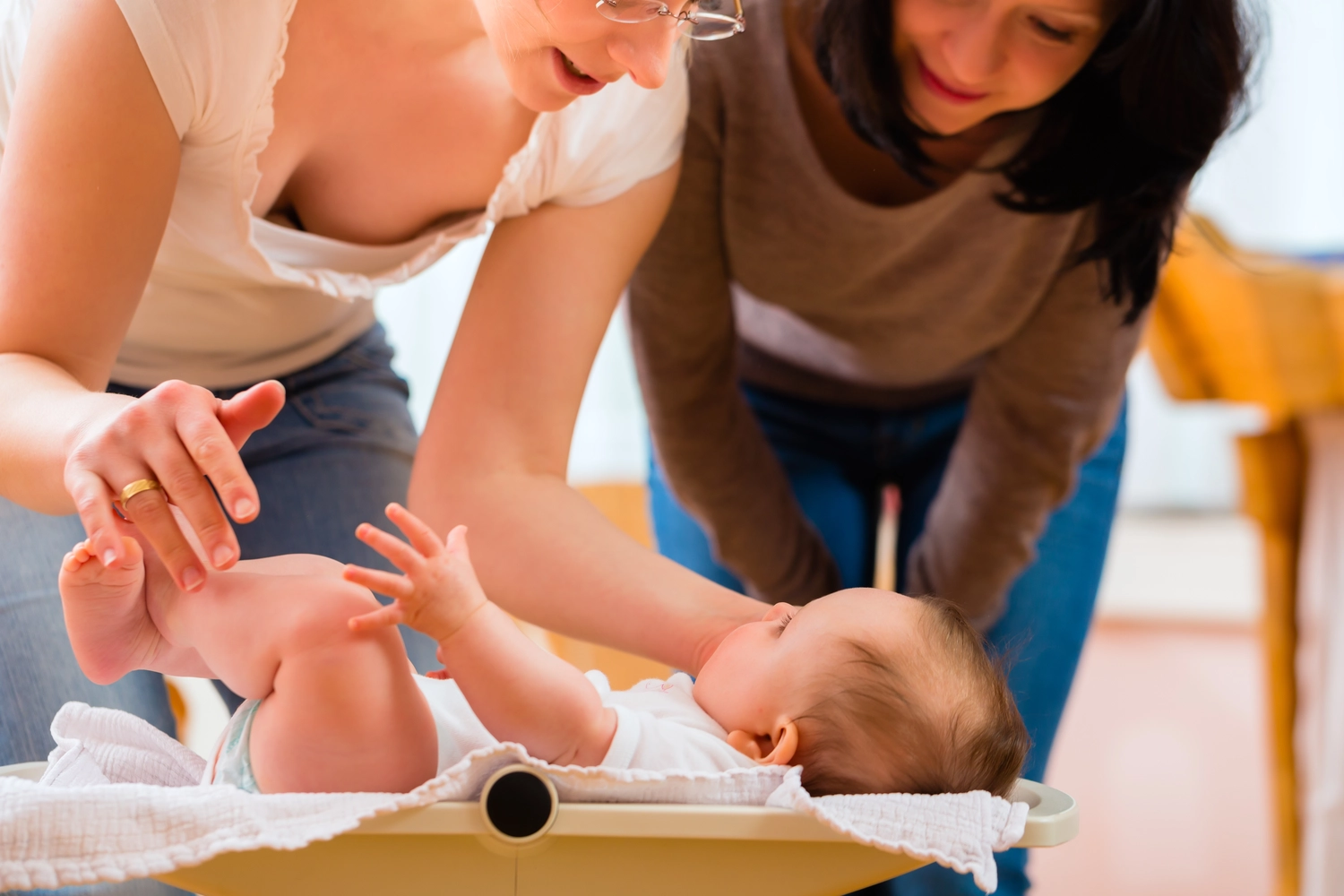 Antonia Schäffler - Hebammenpraxis Eggenfelden - Dieses Bild zeigt eine medizinische Fachkraft, möglicherweise eine Hebamme oder einen Gesundheitsbesucher, wie sie ein neugeborenes Baby auf einer Waage wiegt.